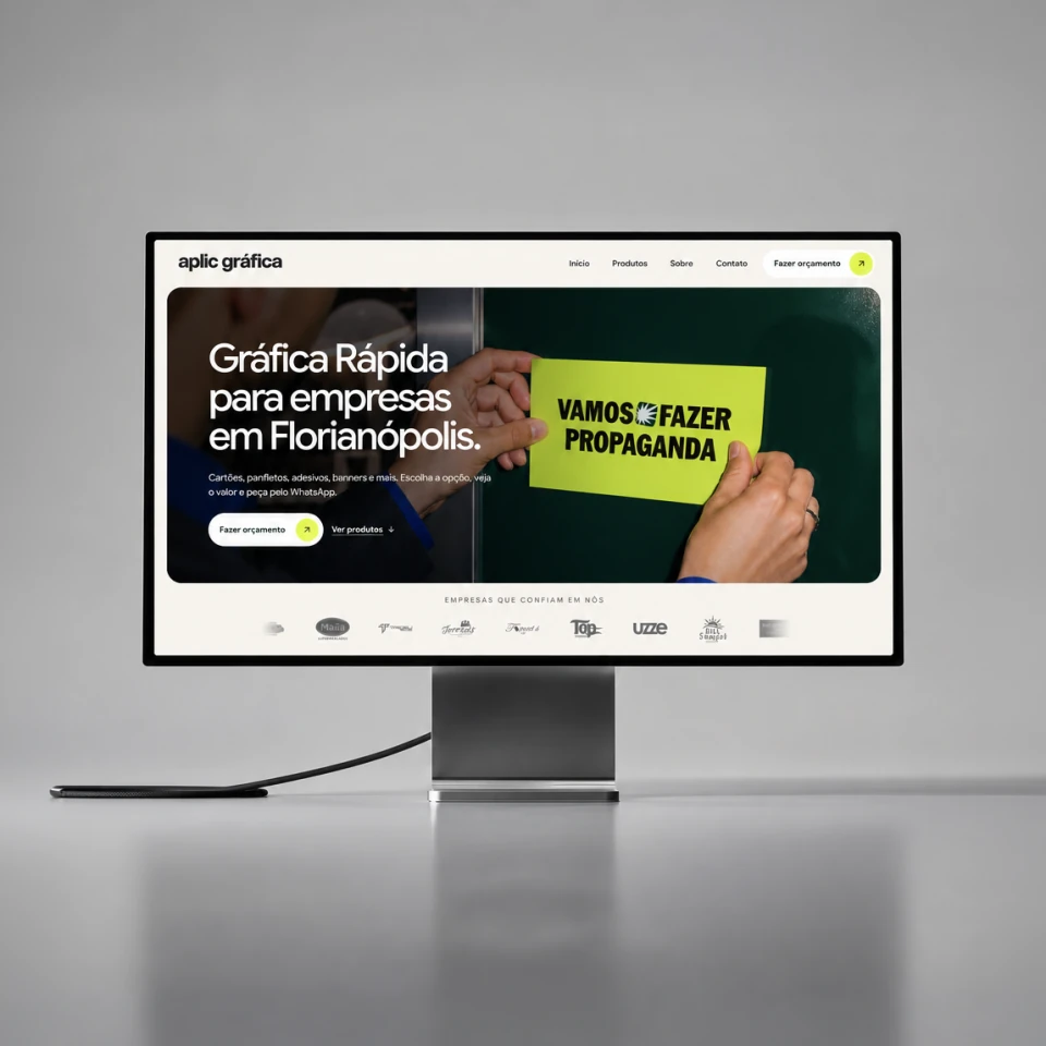 Aplic Gráfica website on a Studio Display on a desk